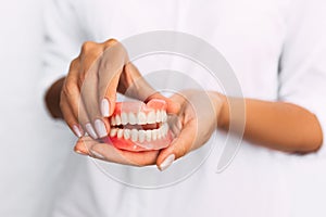 The dentist is holding dentures in his hands. Dental prosthesis in the hands of the doctor close-up. Front view of complete photo