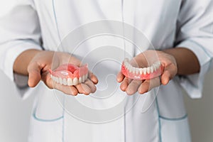 The dentist is holding dentures in his hands. Dental prosthesis in the hands of the doctor close-up.