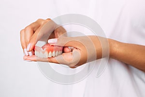 The dentist is holding dentures in his hands. Dental prosthesis in the hands of the doctor close-up. Dentistry conceptual photo.