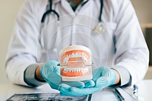 Dentist holding dentures in office room photo