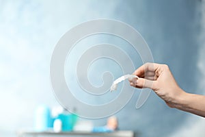 Dentist holding teeth cover in hand on blurred background.