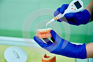 Dentist holding teeth model denture, showing with diagnostic periodontal probe and explaing to the patient what pulpitis looks lik