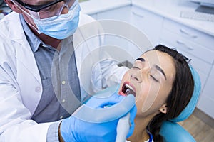 Dentist holding tools while treating woman at medical clinic