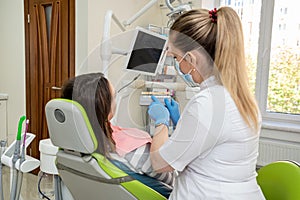 Dentist holding tooth samples for bleaching treatment choosing a shade for her young woman patient