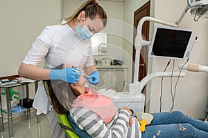 Dentist holding tooth samples for bleaching treatment choosing a shade for her young woman patient