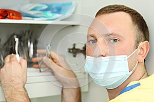 Dentist holds dental instruments and looks