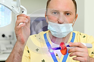Dentist holds ultraviolet curing light tool photo