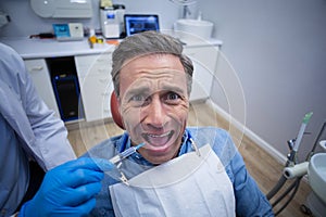 Dentist injecting anesthetics in scared male patient mouth photo
