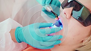 Dentist installs light-curing seal in dentistry to patient woman.