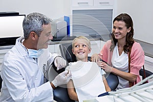 Dentist interacting with mother and son while dental examination