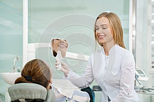 Dentist keeping mirror and showing client beautiful smile