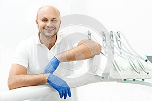 Dentist leaning on the tray of dental instruments