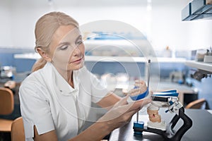 Dentist looking closely at fresh cast model of teeth.