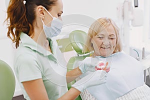 Dentist looking her old patient with tools