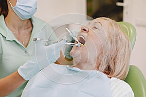 Dentist looking her old patient with tools