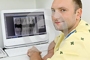 Dentist looks at camera and sits with teeth X-rays photo