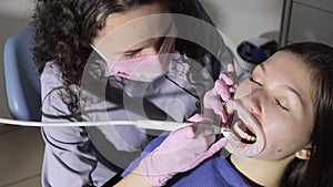 Dentist making professional teeth cleaning female young patient at the dental office. Close-up plan