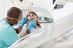 Dentist male in uniform is examinating of female in clinic