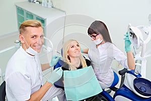 The dentist man and assistant woman are treating teeth to cli