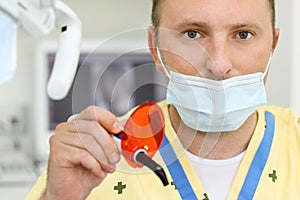 Dentist in mask with ultraviolet curing light tool photo