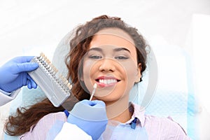 Dentist matching patient`s teeth color with palette