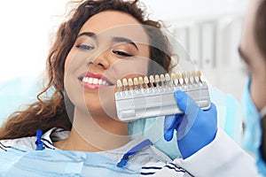 Dentist matching patient`s teeth color with palette