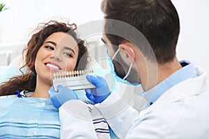 Dentist matching patient`s teeth color with palette