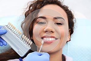 Dentist matching patient`s teeth color with palette