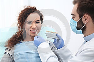 Dentist matching patient`s teeth color with palette