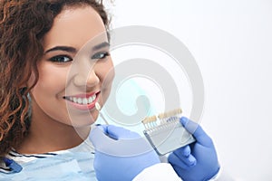 Dentist matching patient`s teeth color with palette in office.