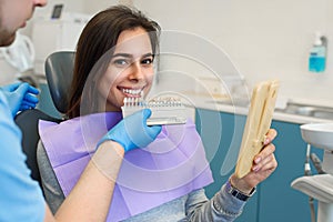 Dentist matching patient`s teeth color with palette in office