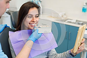 Dentist matching patient`s teeth color with palette in office