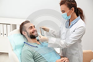 Dentist matching young man`s teeth color with palette