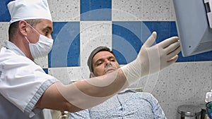 Dentist in medical uniform moving x-ray image on the screen