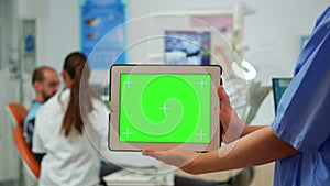 Dentist nurse holding tablet with greenscreen display