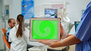 Dentist nurse holding tablet with greenscreen display