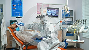 Dentist nurse in potective suit controlling patient temperature