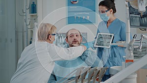 Dentist and nurse showing x ray results to patient with toothache