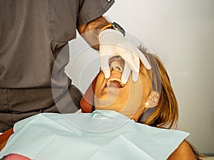 Dentist opens the mouth of his patient and begins to revise the interior helped by his instruments