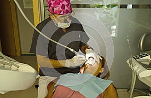 Dentist opens the mouth of his patient and begins to revise the interior helped by his instruments