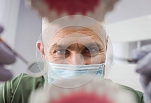 Dentist over open patient`s mouth looking in teeth. Oral care. I