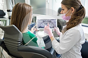 Dentist and patient examining x-ray picture in dental clinic. Doctor showing thumbs up to patient. Dentistry