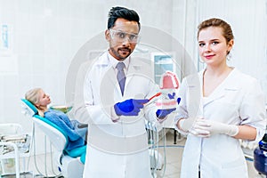 Two Dentist showing jaw model in clinic