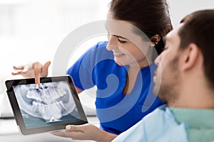 Dentist and patient with teeth x-ray on tablet pc