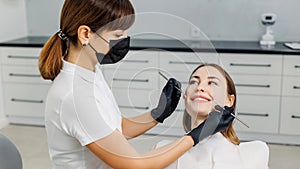 Dentist with patient during teeth treatment. Modern dental clinic. Smiling woman with white teeth during medical examination.