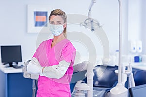 Dentist in pink scrubs looking at camera with arms crossed