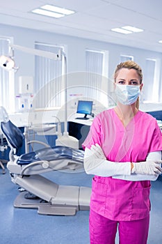 Dentist in pink scrubs standing with arms folded
