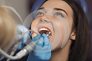 Dentist polishing patient teeth at the dental office.