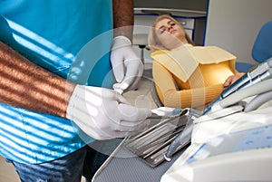 Dentist preparing for the medical examination with young woman patient wearing medical gloves in the dental office. Young female