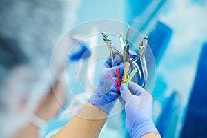 Dentist in protective workwear holding stainless steel dental tools for oral examination and dental treatment